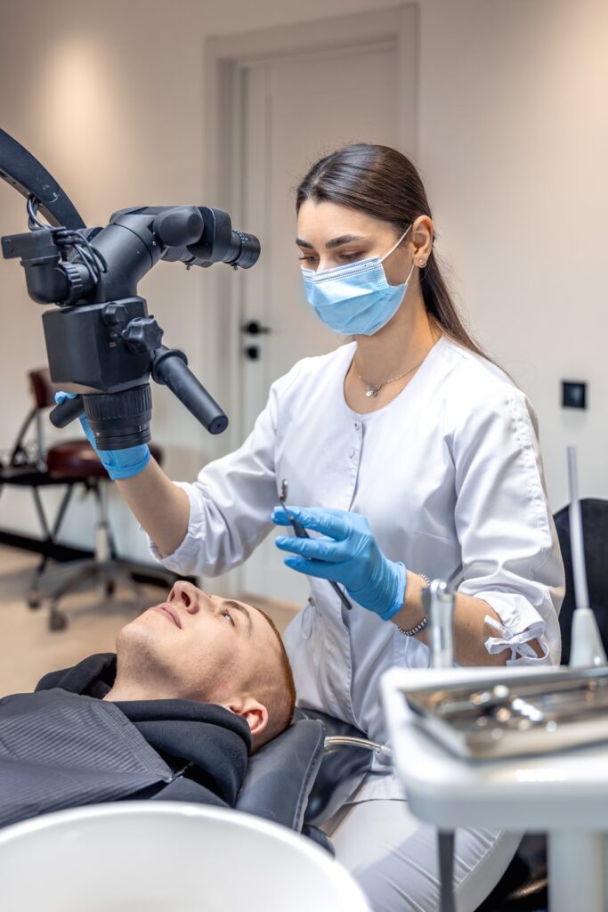 Dentist using microscope on young adult patient, Tijuana