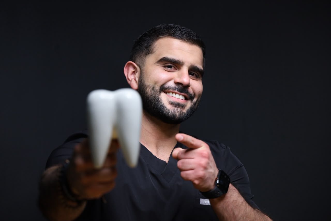 Dentist holding an oversized tooth model at Makeover Dental Studio in Tijuana