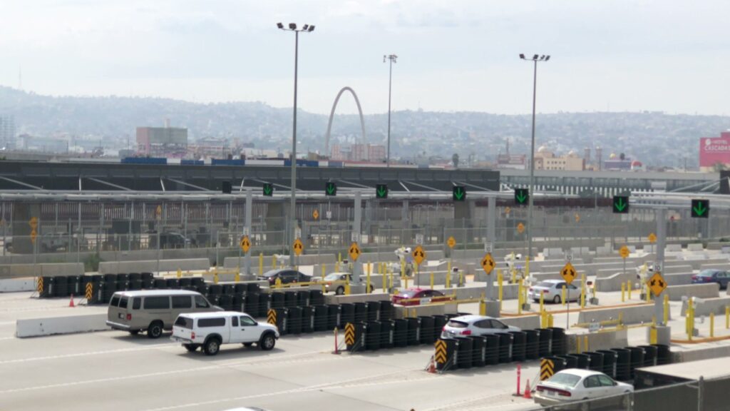Vehicle inspection lanes at the San Ysidro port of entry, with the Tijuana Monumental Arch on the skyline