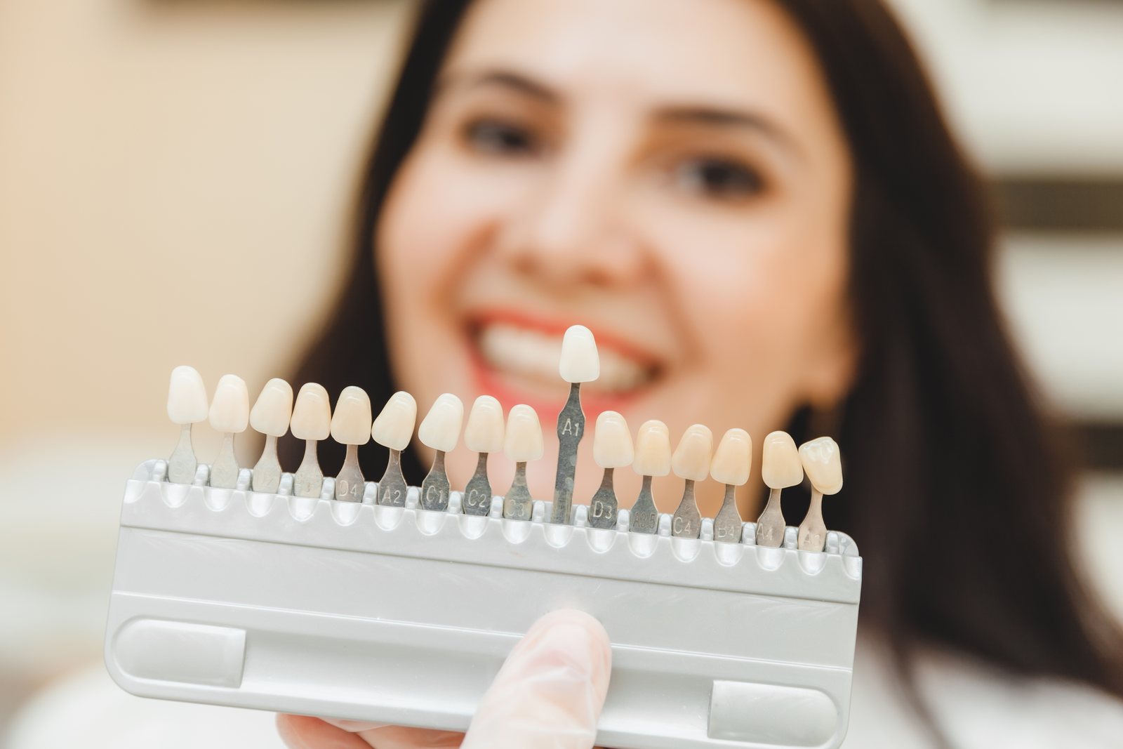 Woman smiling holding teeth shade guide in office, Tijuana